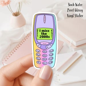 May include: A 3-inch waterproof glossy vinyl sticker featuring a cartoon illustration of a vintage mobile phone with a rainbow gradient background. The phone's screen displays the text "I miss the 2000s".