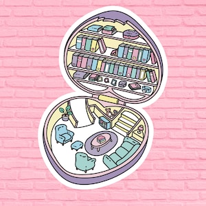 May include: A whimsical heart-shaped trinket box with a colorful interior. The top opens to reveal a miniature bookshelf filled with books, a teddy bear, and other small items. The bottom half of the box features a miniature living room with a couch, armchair, and a coffee table.