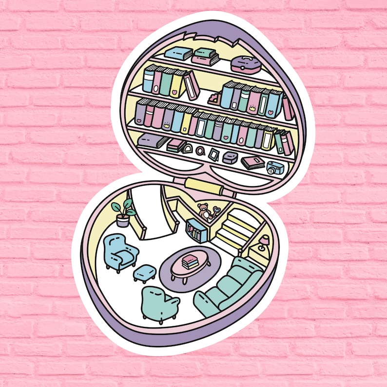 May include: A whimsical heart-shaped trinket box with a colorful interior. The top opens to reveal a miniature bookshelf filled with books, a teddy bear, and other small items. The bottom half of the box features a miniature living room with a couch, armchair, and a coffee table.