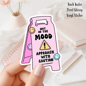 Könnte beinhalten: Rosa-gelber Warnschild-Aufkleber mit dem Text "Nicht in der Stimmung. Mit Vorsicht nähern." und Smileys. 7,6 cm wasserfester, glänzender Vinyl-Aufkleber.