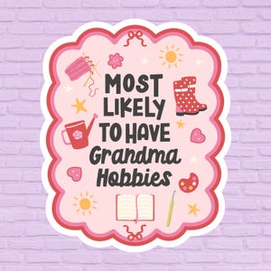 May include: A sticker with a pink and red scalloped border, featuring the text "MOST LIKELY TO HAVE Grandma Hobbies." The design includes illustrations of knitting needles, a watering can, a boot, and other craft-related icons.