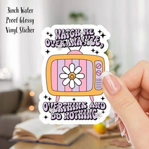 May include: A 3-inch waterproof glossy vinyl sticker featuring a retro TV design. The TV has a pink and purple screen with a daisy on it. The text on the sticker reads "Watch me overanalyze, overthink and do nothing".