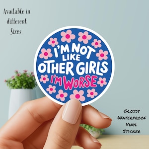 以下が含まれることがあります： 青い丸いステッカー。白い文字とピンクの花で「I'M NOT LIKE OTHER GIRLS I'M WORSE」と書かれています。光沢があり、防水性があります。