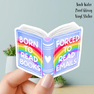 Peut inclure: Un autocollant en vinyle brillant et imperméable de 7,6 cm en forme de livre ouvert. La couverture bleu clair présente un arc-en-ciel et le texte "BORN TO READ BOOKS" et "FORCED TO READ EMAILS". Un cœur blanc est au centre.