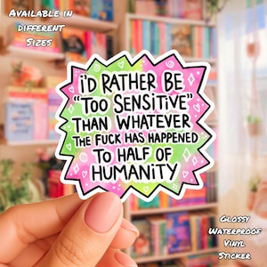 May include: A die-cut sticker with a jagged, starburst-like edge featuring a gradient of pink and green. The sticker displays the black text: I'D RATHER BE "TOO SENSITIVE" THAN WHATEVER THE FUCK HAS HAPPENED TO HALF OF HUMANITY, accented by small hearts and stars.