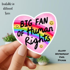 May include: A heart-shaped sticker with the text "BIG FAN OF Human Rights" in black, over a rainbow design. The sticker has a pink background and yellow smiley faces. The sticker is glossy and waterproof.