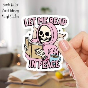 May include: A 3 inch water proof glossy vinyl sticker featuring a skeleton wearing a pink hoodie and holding a book. The text on the sticker reads "Let me read in peace".
