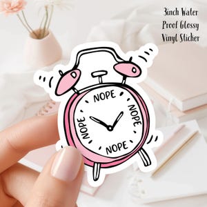 May include: Pink alarm clock sticker with the word "NOPE" written four times around the clock face. The sticker is 3 inches in diameter and is water-proof and glossy.