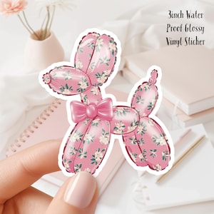 Può includere: Adesivo a forma di cane palloncino rosa con motivo floreale e fiocco rosa. L'adesivo è di 7,6 cm ed è realizzato in vinile lucido impermeabile. Il design presenta uno sfondo rosa chiaro con accenti floreali bianchi e verdi.
