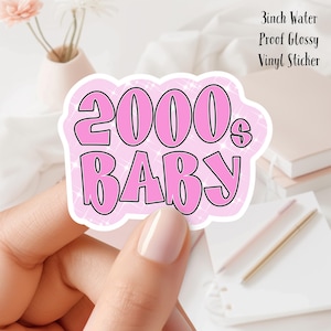 Puede incluir: Pegatina de vinilo rosa con el texto "2000's BABY" sobre un fondo rosa brillante. Pegatina de vinilo brillante impermeable de 7,6 cm.