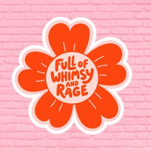 May include: A sticker featuring a stylized orange flower with a white border. The flower's center contains the text "Full of Whimsy and Rage" in a playful font. The background is a pink brick wall.