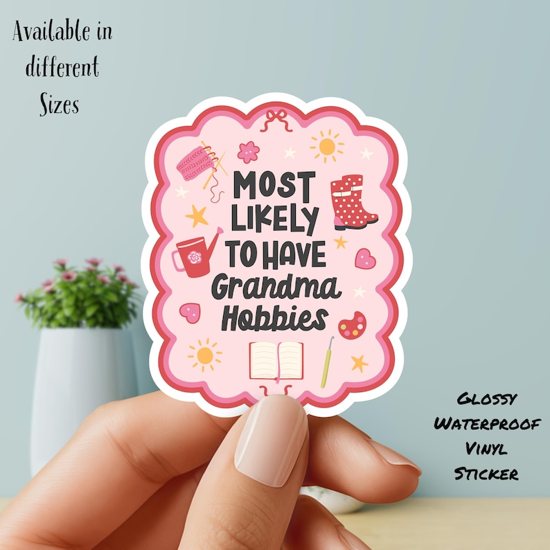 May include: A pink, glossy, waterproof vinyl sticker with a scalloped edge. The sticker reads "MOST LIKELY TO HAVE Grandma Hobbies" with illustrations of knitting, gardening, and painting. Text at the top says "Available in different Sizes".