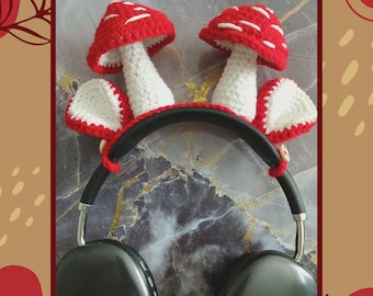May include: Crocheted mushroom headphone covers in red and white. The covers are attached to a pair of black headphones. The image includes the text "CROCHET PATTERN BY AEROL KNOX" and "PDF WRITTEN PATTERN".