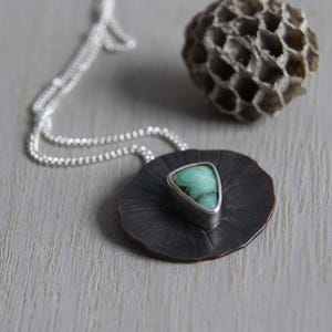 May include: A silver chain necklace with a copper pendant featuring a triangular green gemstone set in silver.