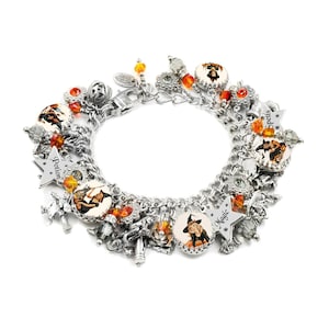May include: A silver-tone charm bracelet featuring multiple round charms with illustrations of witches, orange and clear crystal beads, and star-shaped charms engraved with the words Potion, Magic, and Spells, all connected by a sturdy metal chain.