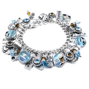 May include: A silver charm bracelet with multiple charms featuring coffee-themed designs, including "Espresso", "Morning Coffee", "I Love Coffee", and "Cappuccino". The charms are silver with blue and white enamel and some have brown glass beads.