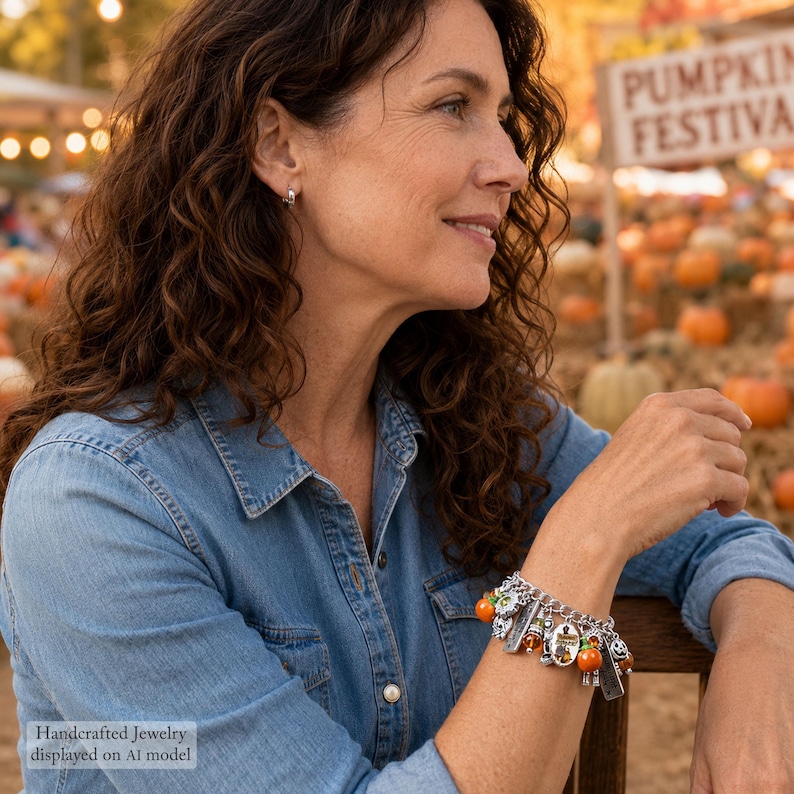May include: A silver-toned charm bracelet featuring multiple dangling charms, including small orange pumpkin beads, metallic pumpkin shapes, and rectangular silver tags, all attached to a classic silver link chain with a secure clasp.