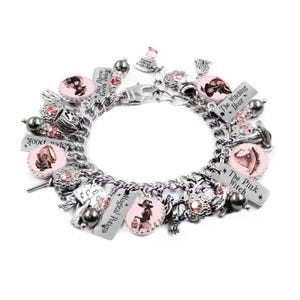 May include: A silver charm bracelet featuring multiple round pink-toned charms with illustrations of witches, hats, and potions. Rectangular silver tags are engraved with the text "Sky Above Earth Below," "Magical Potions," "The Witching Hour," and "The Pink Witch."