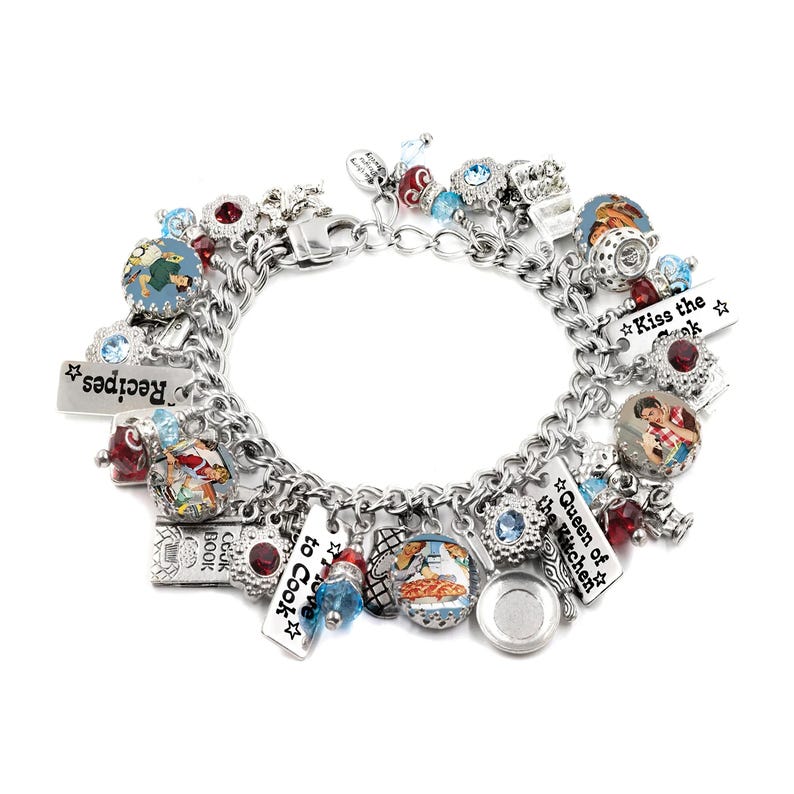 A silver charm bracelet adorned with various charms, including a heart-shaped charm, a star-shaped charm, and a charm with a picture of a woman. The bracelet also features a charm with the text "Kiss the Cookbook" and another charm with the text "Queen of the Kitchen".