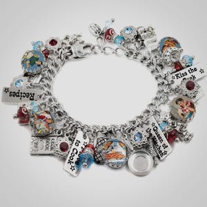 A silver charm bracelet adorned with various charms, including a heart, a book, and a bird, as well as other decorative elements.