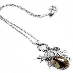 a silver necklace with various charms and pendants, including a charm that says "Bosco" and a charm depicting a dog.