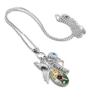 A silver necklace with various charms and a pendant featuring a dog image.