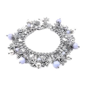 May include: A silver-toned charm bracelet featuring multiple snowflake-shaped charms and round, light blue, semi-translucent beads. The bracelet is constructed with a thick chain link design and includes a secure lobster claw clasp closure.