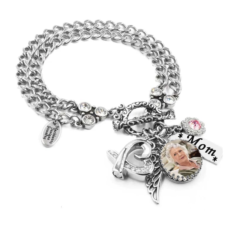 A silver-toned charm bracelet with various charms, including a heart-shaped charm, a charm with a photo of a person, and a charm with the word "Mom".