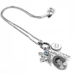 a silver necklace with various charms and a pendant, including a small picture of a man and some text.