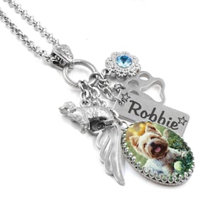 A silver necklace with various charms and a pendant featuring a picture of a dog.
