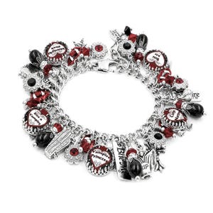May include: A silver-tone charm bracelet featuring various themed pendants including a coffin, vampire fangs, and circular charms with red and black accents. Text on charms includes "Kiss a Vampire," "Vampire Princess," "Bite Me," and "Carpe Noctem."