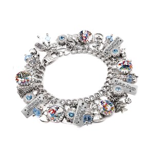 Op de afbeelding: Een zilverkleurige bedelarmband met diverse winterse bedels, waaronder ronde afbeeldingen van sneeuwpoppen, blauwe kristallen, sneeuwvlokvormen en rechthoekige metalen labels met de tekst "Let it Snow!", "Winter Wonderland" en "We could build a snowman".