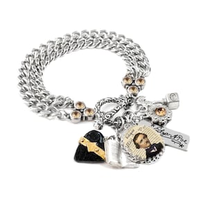 A silver-toned charm bracelet with various charms and a pendant featuring a portrait of a man.