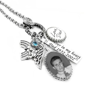 A silver-toned necklace with various charms and pendants, including a charm with a photo of a man and a charm with the words "Love Dad" written on it.