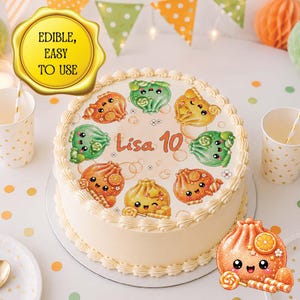 May include: A round cake featuring an edible topper with the text 'Lisa 10' surrounded by illustrations of smiling, anthropomorphic dumplings in orange and green colors. The cake has white frosting with decorative piping along the top edge.