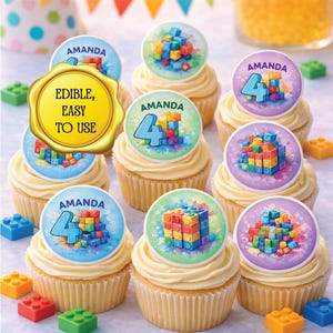 May include: Cupcakes with buttercream frosting, topped with edible decorations featuring colorful block designs and the name "Amanda" with the number "4". The cupcakes are surrounded by colorful block-shaped candies. The text "Edible, Easy to Use" is also visible.