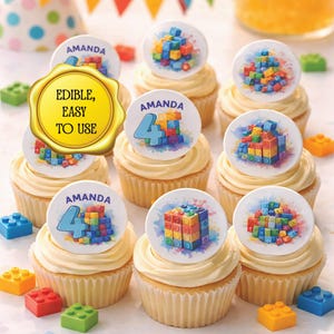 Puede incluir: Cupcakes de vainilla con decoraciones comestibles con diseños de bloques de construcción coloridos, el nombre "Amanda" y el número "4". Los cupcakes están rodeados de juguetes de bloques de construcción coloridos.