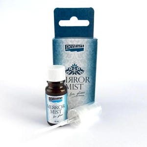 Pode incluir: Uma garrafa de vidro castanho com tampa branca e rótulo azul que diz "MIRROR MIST for glass". A garrafa está ao lado de uma caixa azul com a marca "pentart" e o mesmo texto. Um bico de pulverização branco também é visível.