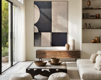 May include: A modern living room with a large abstract painting in black and white on the wall. The painting is made up of geometric shapes and has a minimalist style. The room is decorated in a neutral color palette with a wooden coffee table and two beige poufs.