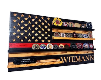 Puede incluir: Estante de exhibición de madera con forma de bandera estadounidense, con tres filas para monedas. El diseño de la bandera tiene un fondo negro con estrellas doradas, una franja roja y el nombre "WIEMANN". También se muestra un cuchillo.