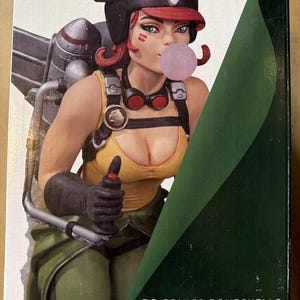 May include: A DC Collectibles Hawkgirl Bombshells numbered limited edition statue box featuring a character with red hair, a black helmet, and a pink bubblegum bubble. The figure wears a yellow tank top, green pants, and a silver jetpack on the back.