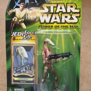 May include: A Star Wars Power of the Jedi Battle Droid Security action figure in original packaging. The card features Obi-Wan Kenobi, the Star Wars logo, and a Jedi Force File. The tan and maroon droid holds a black blaster rifle inside a clear blister.
