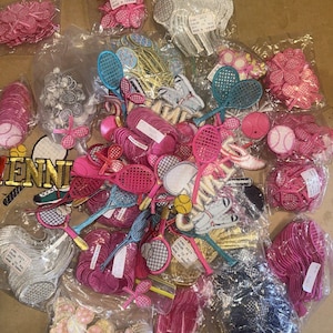 May include: A collection of tennis-themed patches and appliques in various colors. The image includes pink tennis rackets, tennis balls, and tennis shoes. Some patches have the word "TENNIS" in gold lettering.