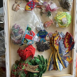 May include: A collection of assorted embroidered fabric patches featuring various designs including tropical palm trees, colorful fish, sailboats, and abstract shapes. Some patches are loose while others are contained in clear plastic bags.