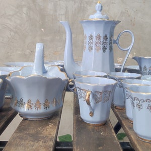 May include: A vintage tea set with a light blue and gold design. The set includes a teapot, creamer, sugar bowl, and six cups and saucers.