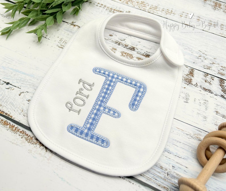 May include: White baby bib with a blue and white gingham letter F and the name Ford embroidered in silver thread.