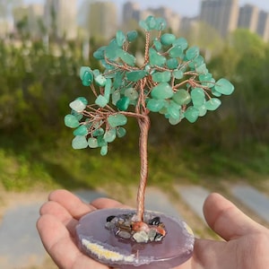Op de afbeelding: Een groene kristallen boom met een koperen draadstam en takken. De boom staat op een paarse agaatbasis met kleinere kristallen rond de basis.