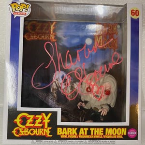 May include: A Funko Pop! Albums vinyl figure of Ozzy Osbourne's "Bark at the Moon" album. The figure is flocked and features a miniature Ozzy figure with red eyes and a snarling expression. The box includes the album art and a pink signature.
