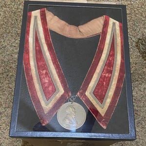 Op de afbeelding: Een witte keramische mok met een zwart handvat en de tekst "But First, Coffee" in een vetgedrukte, zwarte letter. De mok staat tegen een vage achtergrond, wat een gezellige omgeving suggereert.