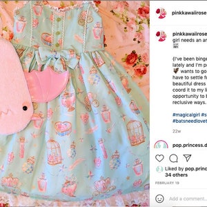 May include: A light blue dress with a pink bow and a print of teacups, birds, and cages. A pink plush bat with wings is lying on the floor next to the dress. The caption reads: "Every magical girl needs an animal companion." #magicalgirl #sweetlolita #lolitafashion #batsneedlovetoo